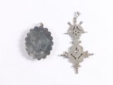 two pieces of silver jewelry on a white surface