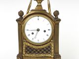 une horloge dorée et noire posée sur une surface blanche