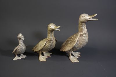 three ducks standing next to each other on a black surface