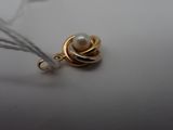 a pearl and gold pendant on a white surface
