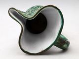 a green and white vase that is on a white surface