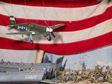 a model of a plane flying over a display of military figures