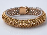 gros plan d'un bracelet en or sur une surface blanche