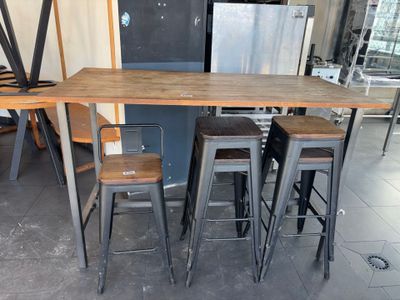 a table with four stools and a refrigerator in the background