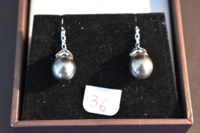 une paire de boucles d'oreilles en perles dans un écrin sur lequel est apposée une étiquette de prix