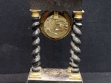 a black and gold clock on a stand on a black background