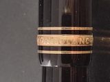 a close up of a fountain pen with a gold band on it