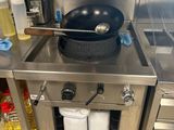un plan de travail en acier inoxydable sur lequel est posée une poêle, dans une cuisine professionnelle