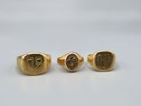 a pair of gold rings with the initials of two men and a woman