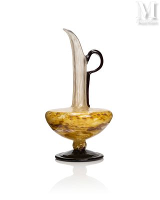 un vase en verre muni d'une anse noire et posé sur un socle
