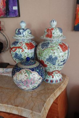 Plusieurs vases sont posés sur une table devant un tableau