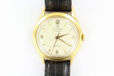 une montre-bracelet en or avec un cadran blanc et un bracelet noir