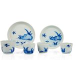 plusieurs assiettes et tasses en porcelaine bleue et blanche posées sur une surface blanche