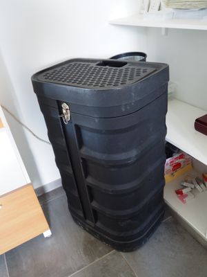 une valise noire posée par terre à côté d'une étagère