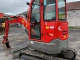 a small red excavator that is parked in a parking lot