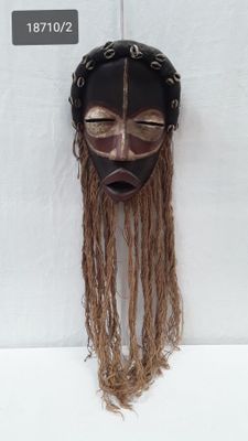 an image of a wooden mask hanging on a white wall