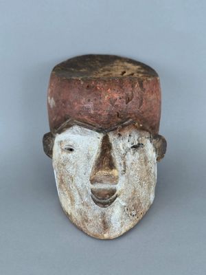 une image représentant un masque en bois coiffé d'un chapeau