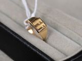 une bague en or dans un écrin noir, attachée par un cordon blanc