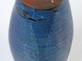 a blue vase with a brown lid sitting on a white surface