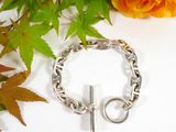a silver bracelet with a cross on it next to a rose