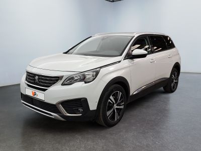Une voiture blanche est garée dans une grande pièce équipée d'un ventilateur de plafond.
