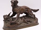 bronze statue of a dog on a rock with a bird in it ' s mouth