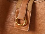the inside of a tan purse with a gold ring on the handle