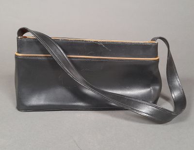 black leather purse with a strap on a grey background
