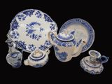 Plusieurs pièces de poterie bleue et blanche sont exposées sur un fond noir