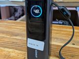 a cell phone sitting on a table with a charger attached to it