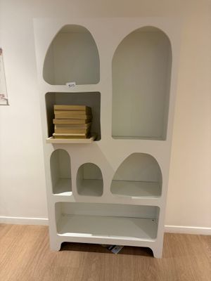 une bibliothèque blanche avec des livres dessus, dans une pièce