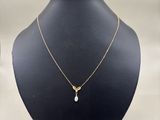 a gold necklace with a pearl on a mannequin neck
