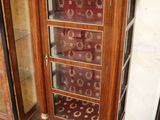 a tall wooden cabinet with a glass door in the corner