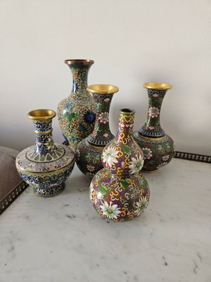 cinq vases posés sur une table, avec un miroir en arrière-plan
