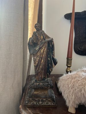 a statue of jesus sitting on a table next to a candle