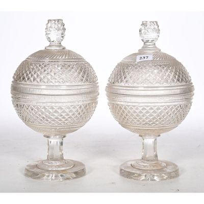 pair of cut glass urns on pedestals on a white background