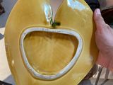 a person holding a yellow heart shaped bowl on a table