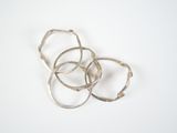 four silver rings on a white surface