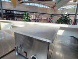 un plan de travail en acier inoxydable équipé d'une plaque de cuisson, situé dans un immeuble
