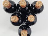 six bottles of wine are arranged in a triangle on a white surface