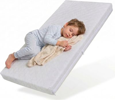 un bébé qui dort sur un matelas, recouvert d'une couverture