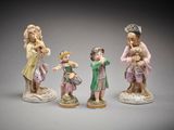 three porcelain figurines of people with hats and dresses on them
