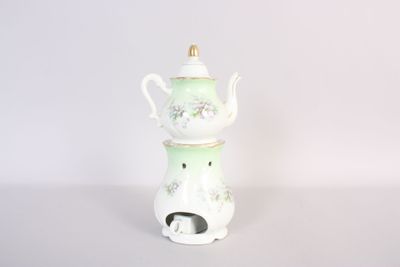 une photo d'une théière blanche et verte posée sur une table blanche