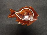 a wooden bowl with a fish on it on a black surface