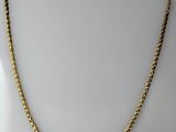 a gold necklace with a twisted rope on a white background