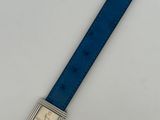 a close up of a watch on a white surface with a blue strap