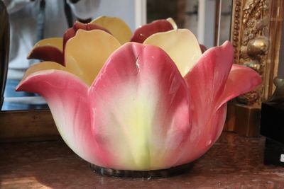 a pink and yellow flower sitting in a vase on a table