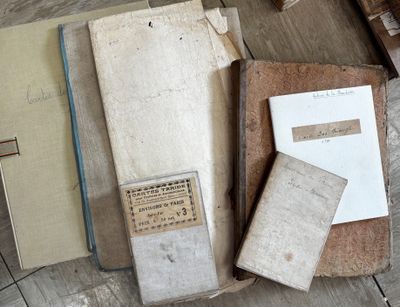 Plusieurs vieux livres sont posés sur une table en bois, à côté d'un stylo et d'une feuille de papier.