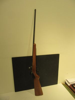 un pistolet et un livre posés sur un bureau, dans une pièce éclairée par une lampe