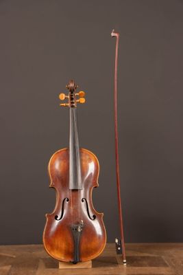 an old violin sitting on top of a wooden table next to a bow